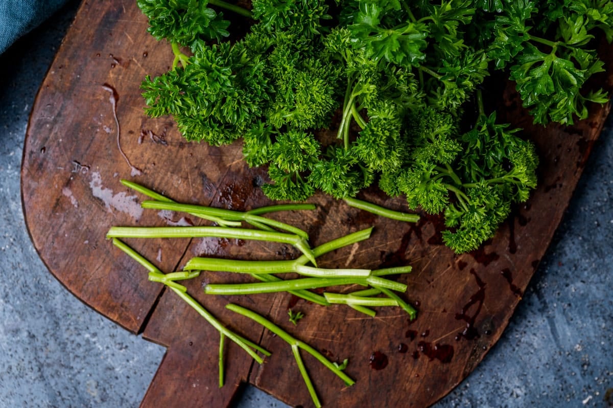 fresh parsley on a cutting board with stems cut off