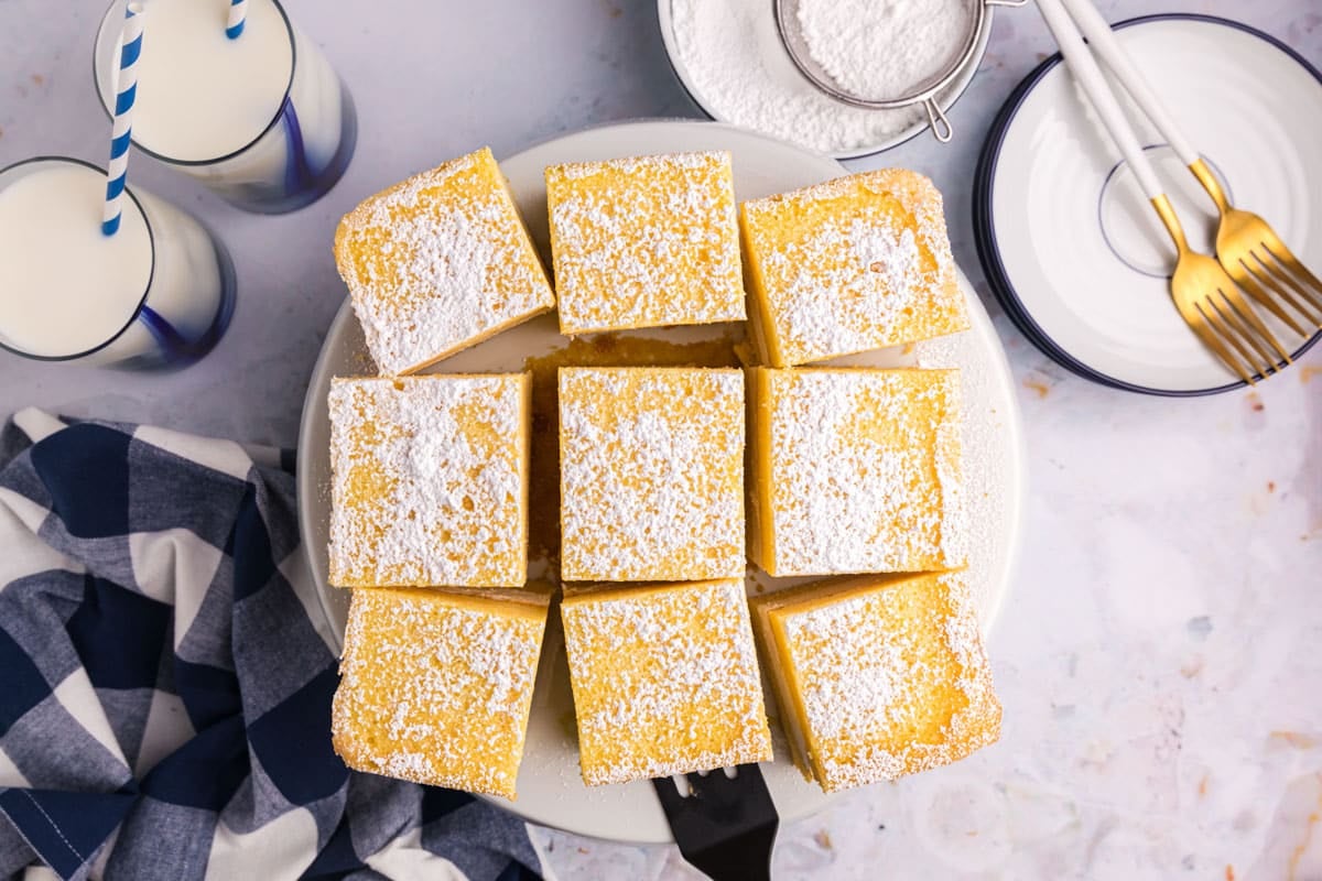 overhead view of a yellow cake cut into squares on a plate