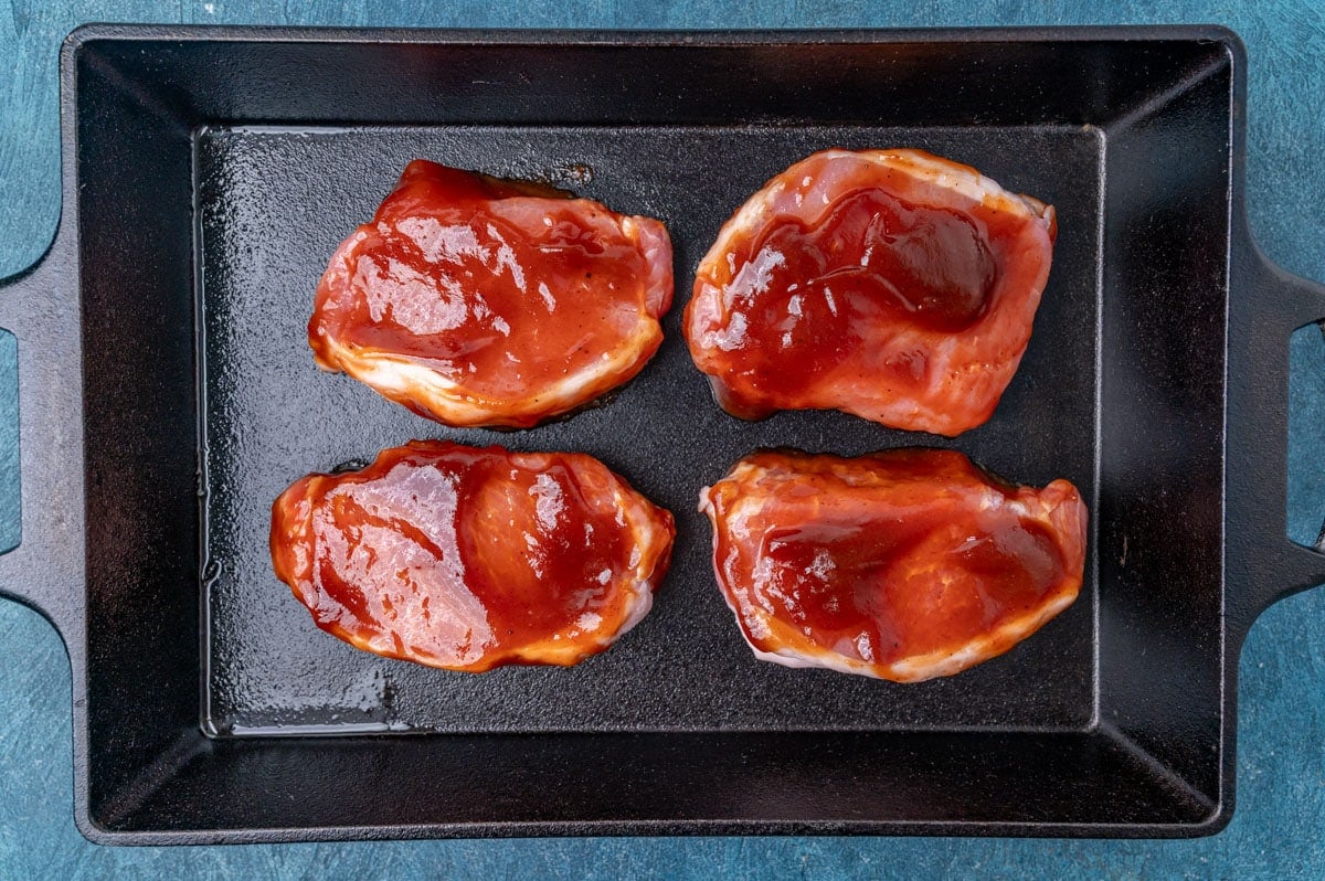 uncooked marinated pork chops in a baking pan