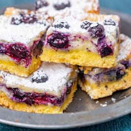 blueberry lemon cheesecake bars stacked on a plate