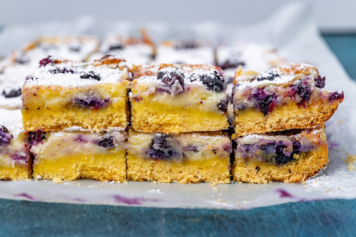 blueberry lemon gooey butter cake cut in squares on parchment paper
