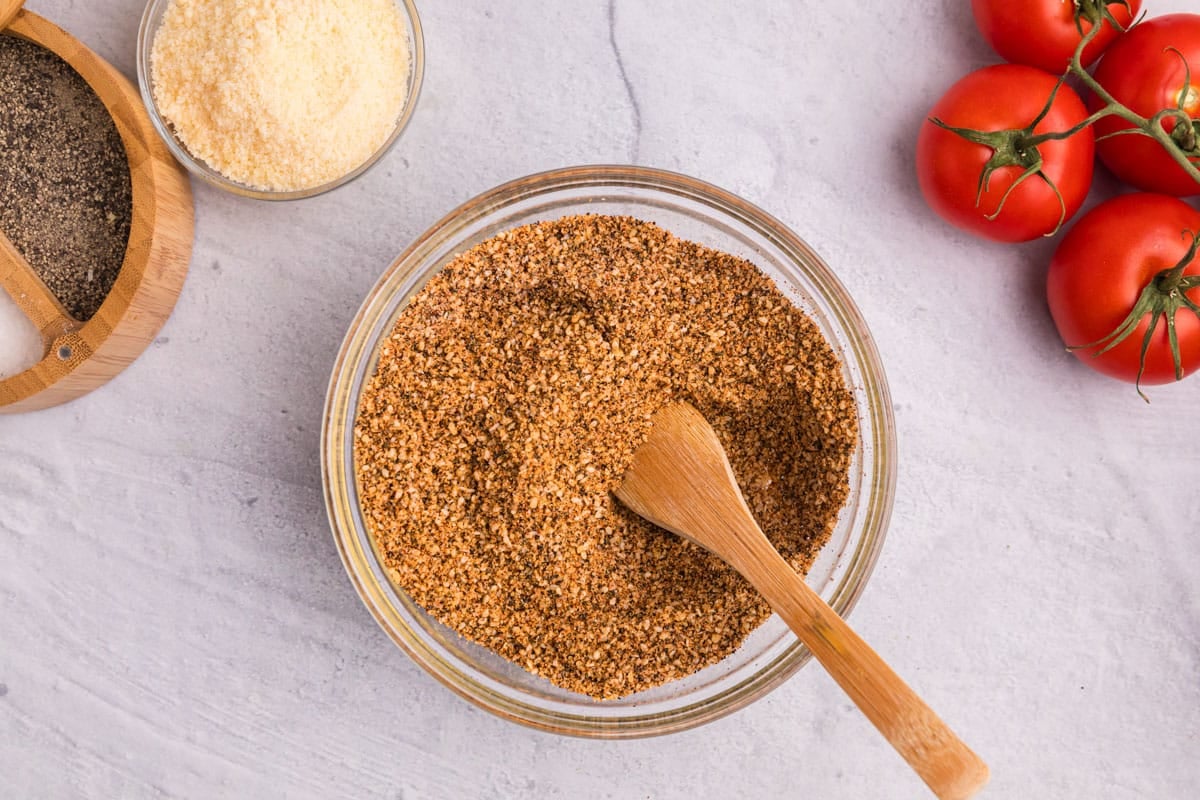 overhead view of a glass bowl of pasta salad seasoning