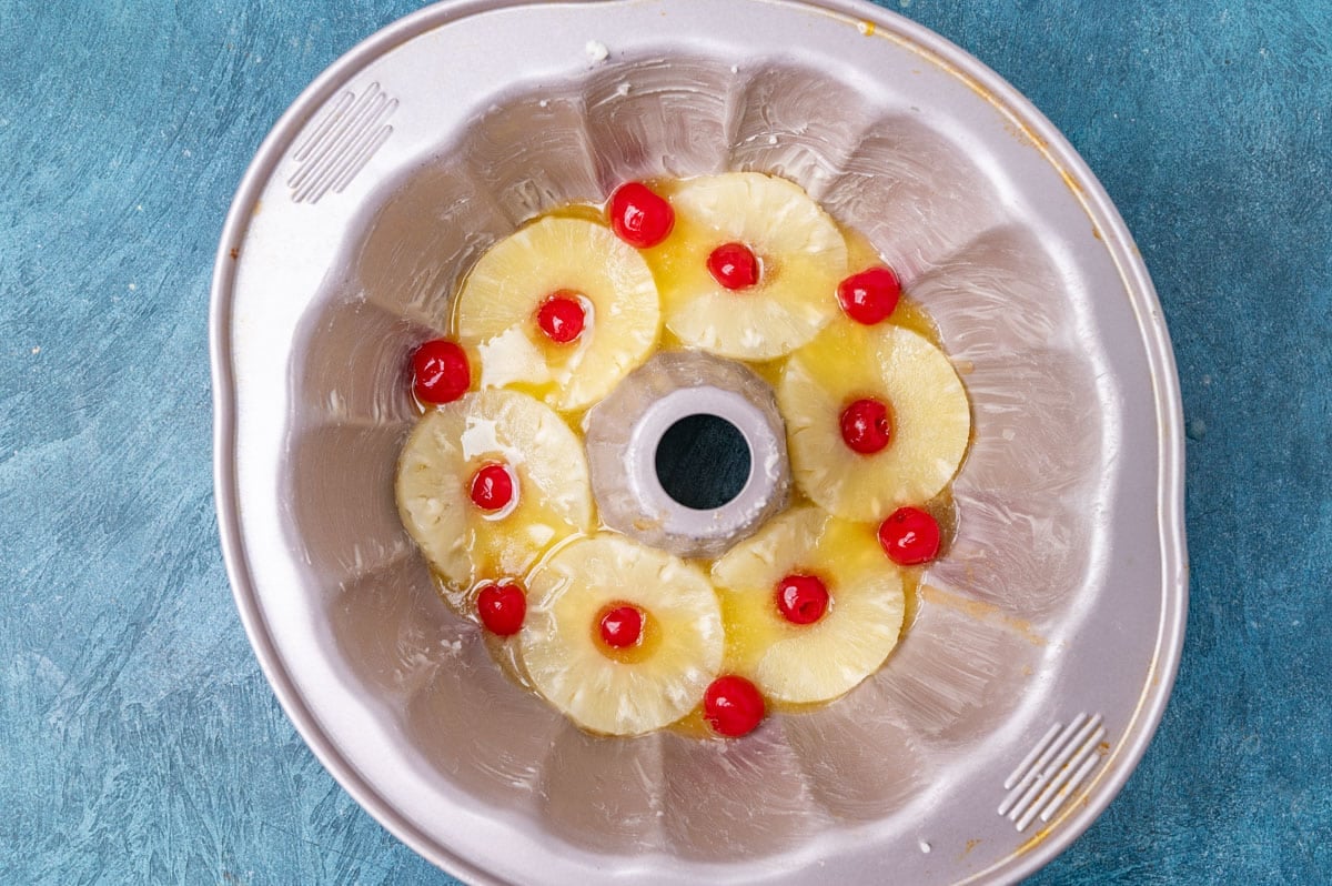 bundt cake pan with pineapple rings and maraschino cherries