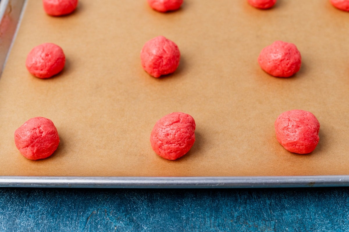 balls of strawberry cookie dough on a baking sheet