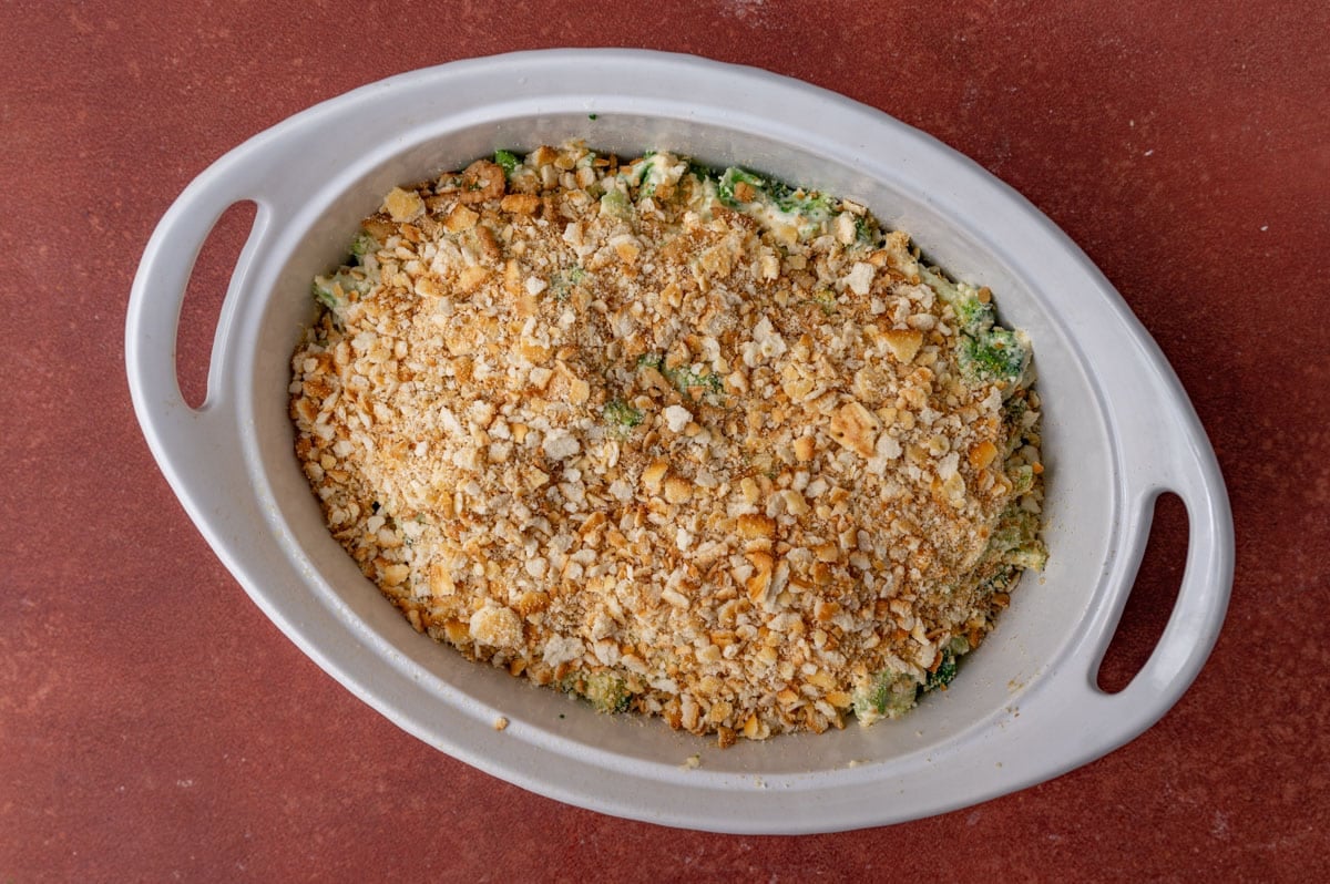 unbaked broccoli casserole with ritz crackers in a white dish