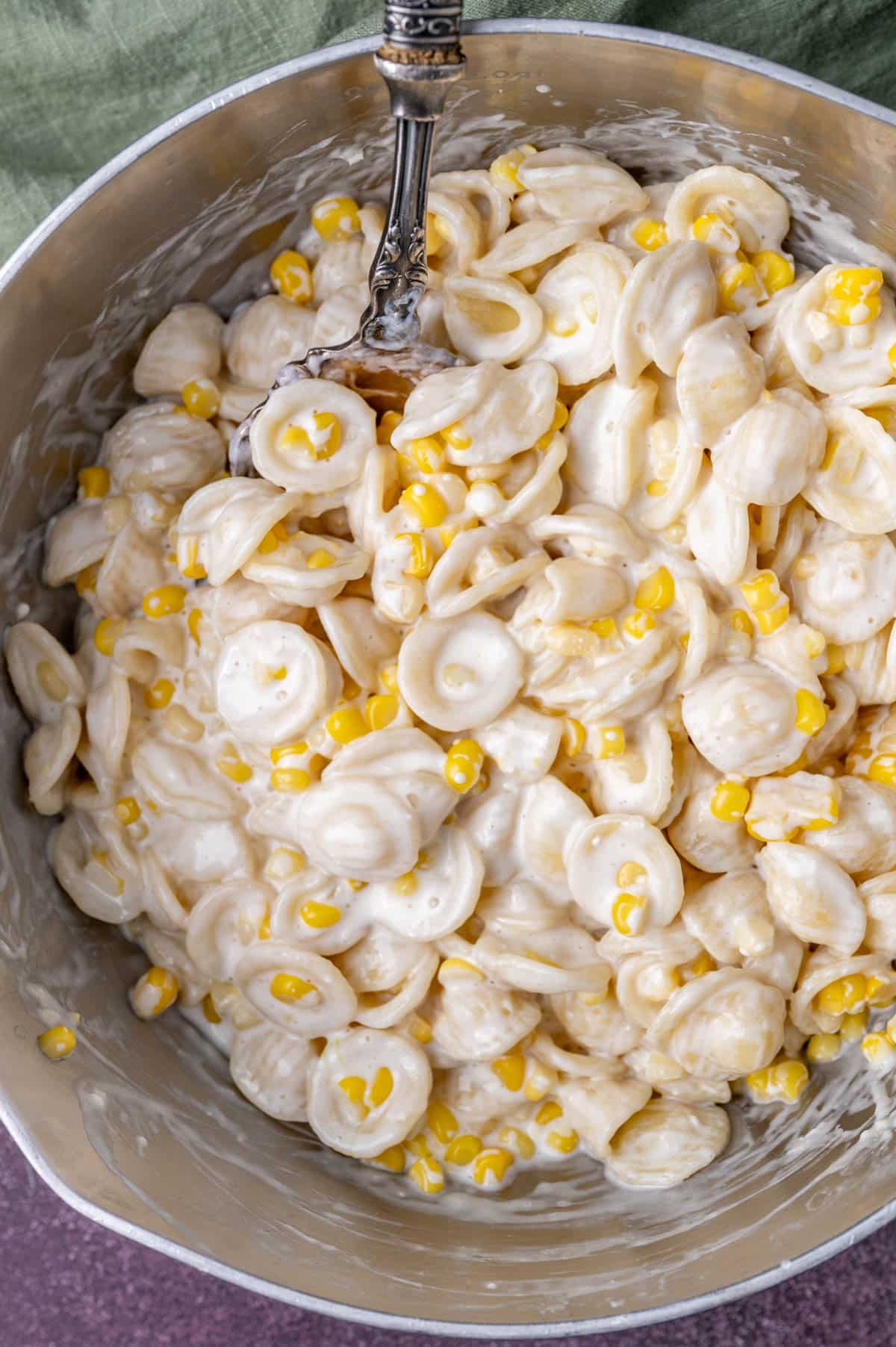 pasta with corn in a saucepan with a spoon