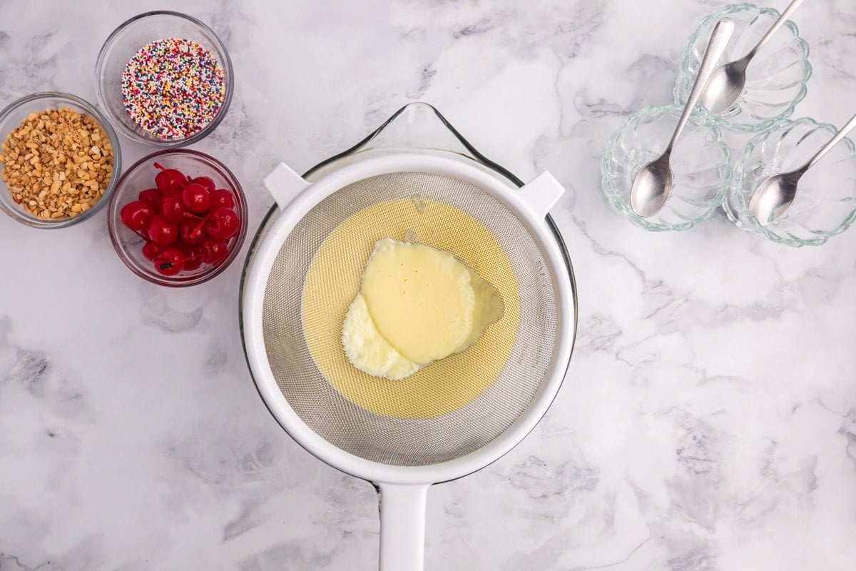 custard mixture straining in a strainer