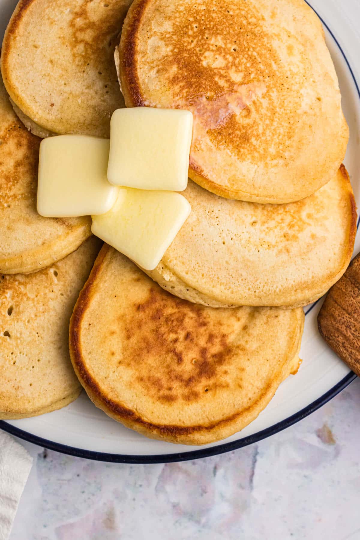 pancakes on a plate with 3 pads of butter on top