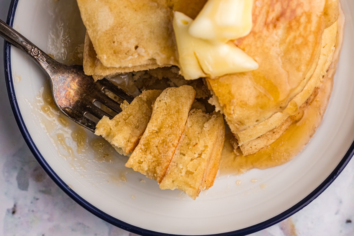 overhead view of a stack of pancakes with one bite on a fork