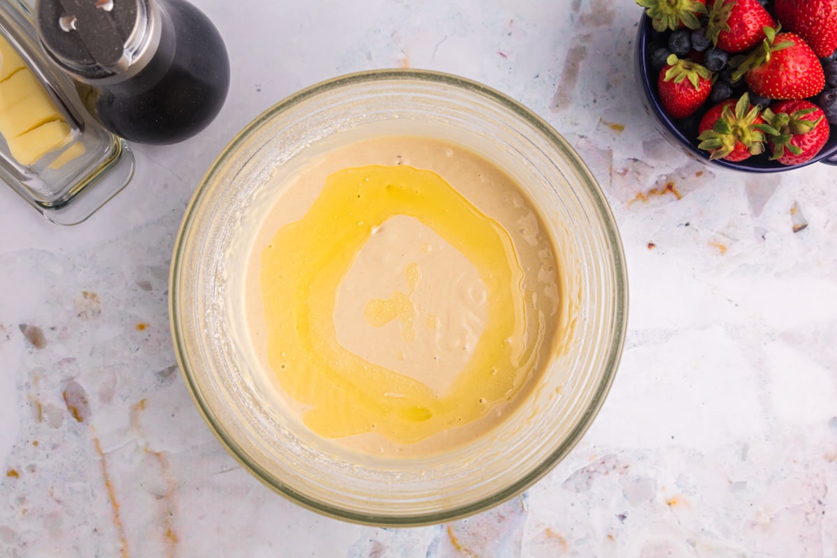 pancake batter in a bowl with melted butter on top