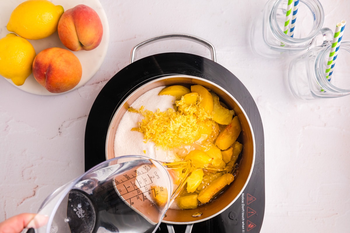 pouring water into a saucepan with peaches and sugar