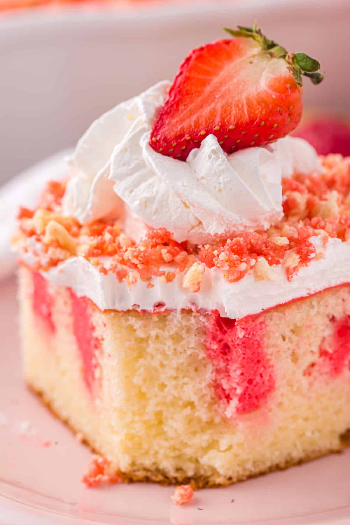 a piece of strawberry crunch poke cake with a bite out of it