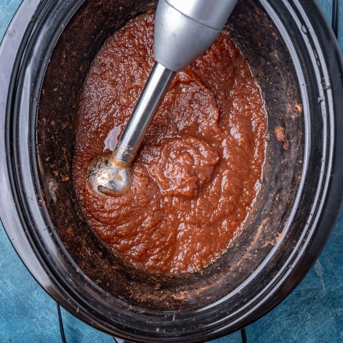 apple butter in a crockpot with an immersion blender