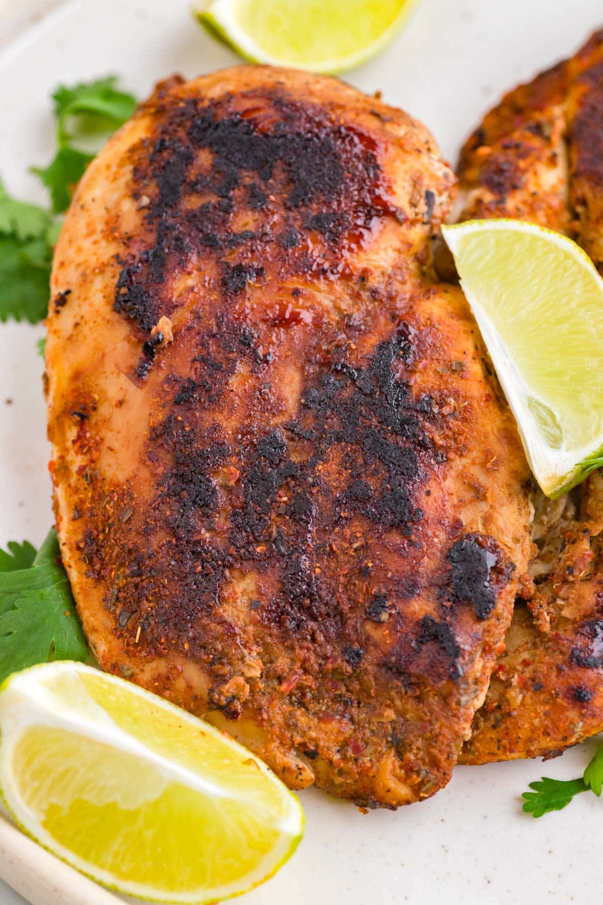 closeup of a piece of blackened chicken with lime wedges