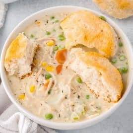 a bowl of chicken pot pie soup with a biscuit on top