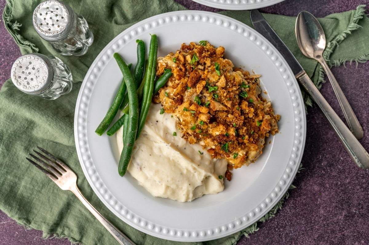 overhead view of a plate of chicken and stuffing with mashed potatoes and green beans