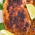closeup of a piece of blackened chicken with lime wedges