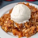 apple crisp on a plate with vanilla ice cream on top