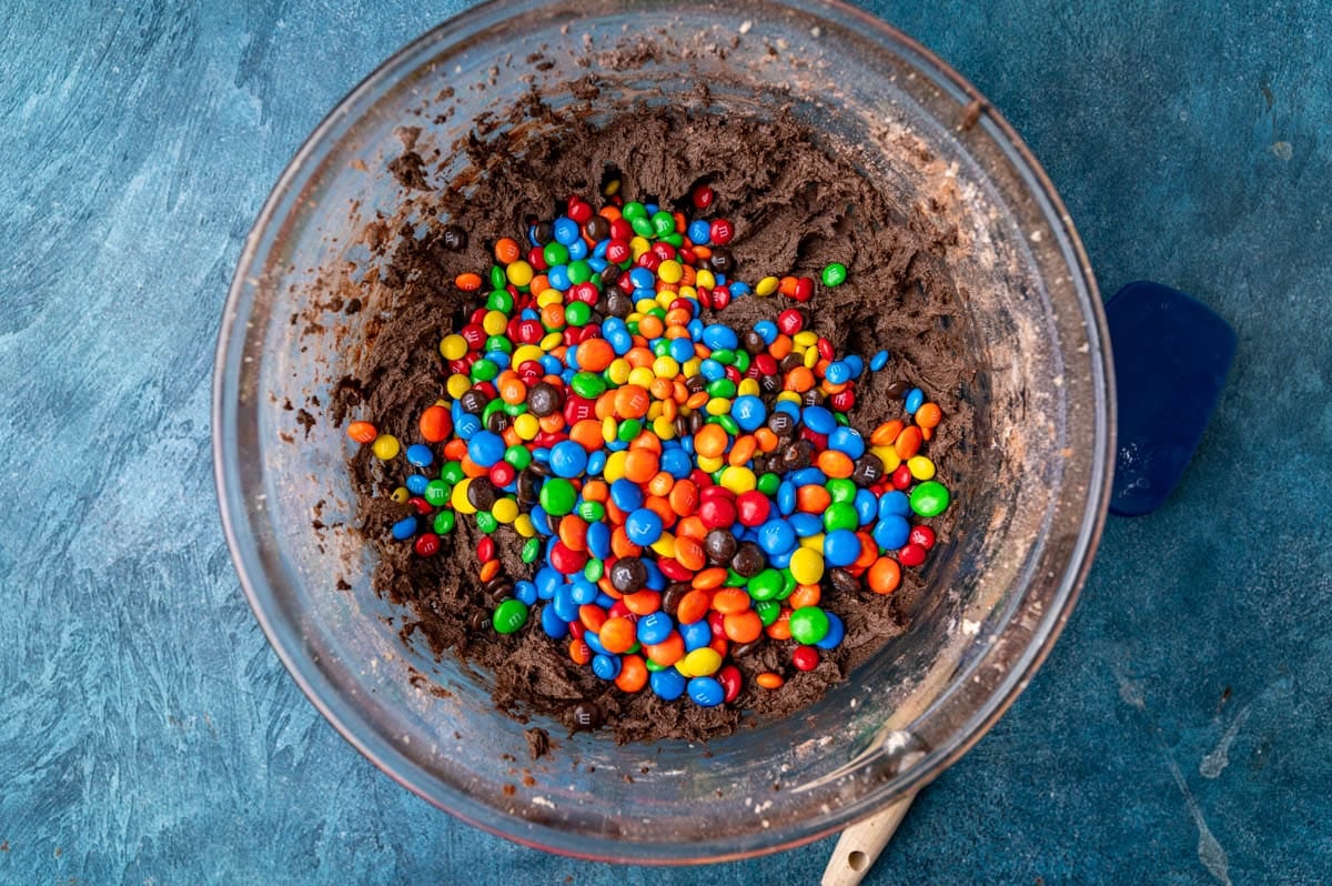 chocolate cookie dough in a glass bowl with M&Ms on top