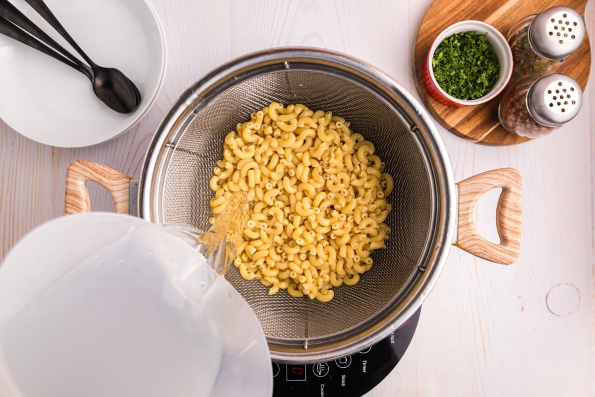 water pouring over cooked pasta in a colander