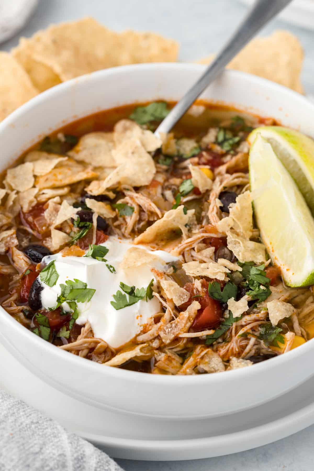 mexican chicken soup with tortilla chips and sour cream on top