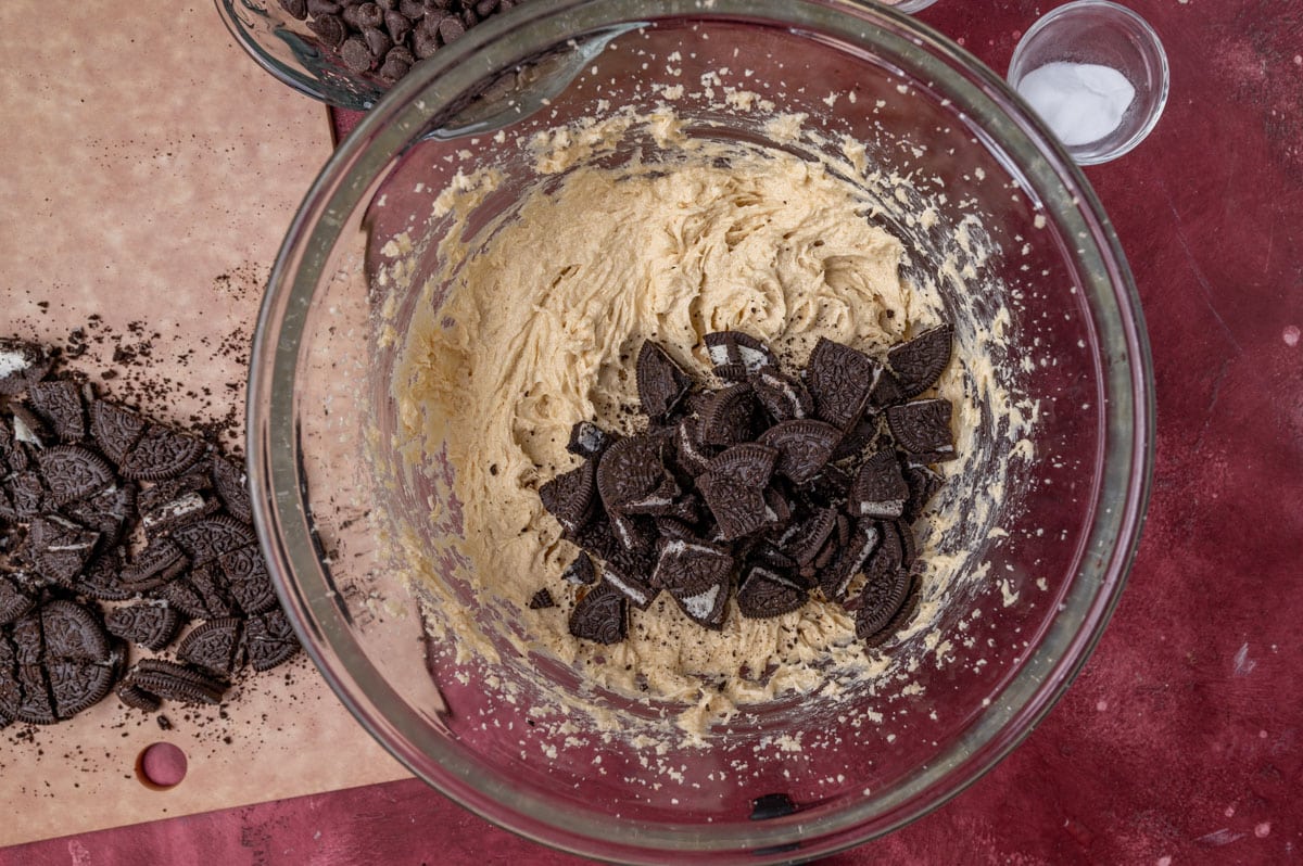 oreo cookie pieces over cookie dough in a glass bowl
