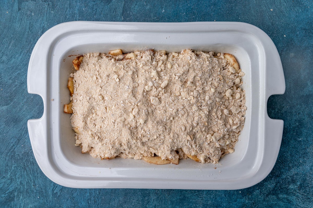 sliced apples and oat streusel for apple crisp in a slow cooker