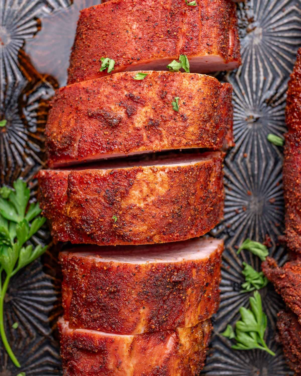 sliced pork tenderloin on a baking sheet with spicy dry rub