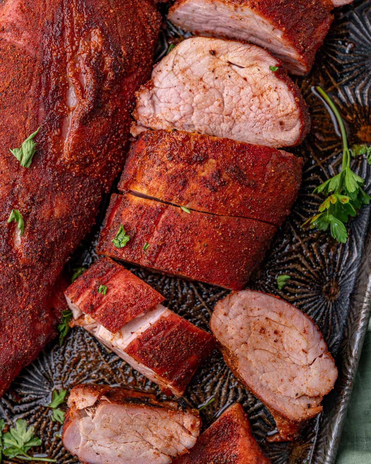 slices of smoked pork tenderloin on a baking sheet with fresh parsley