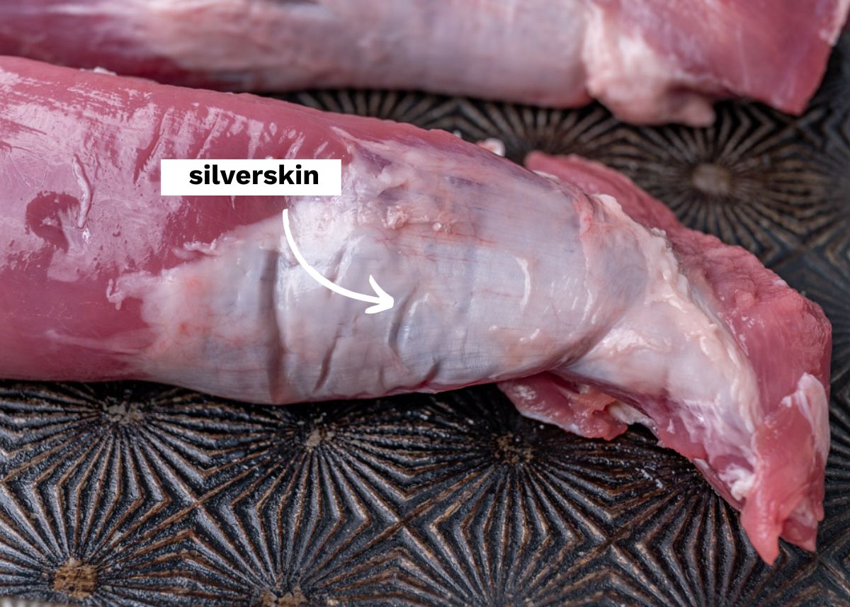 a raw pork tenderloin with a label pointing to the silverskin