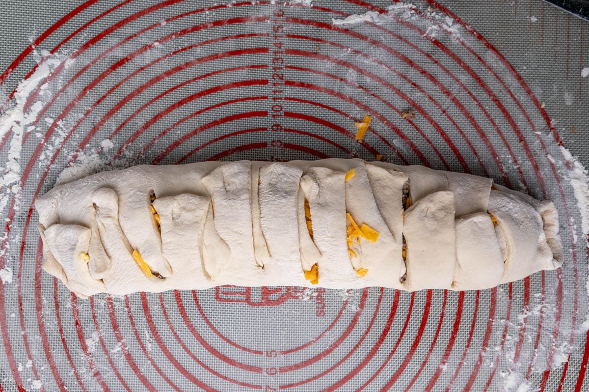 an unbaked stromboli rolled up on a pastry mat