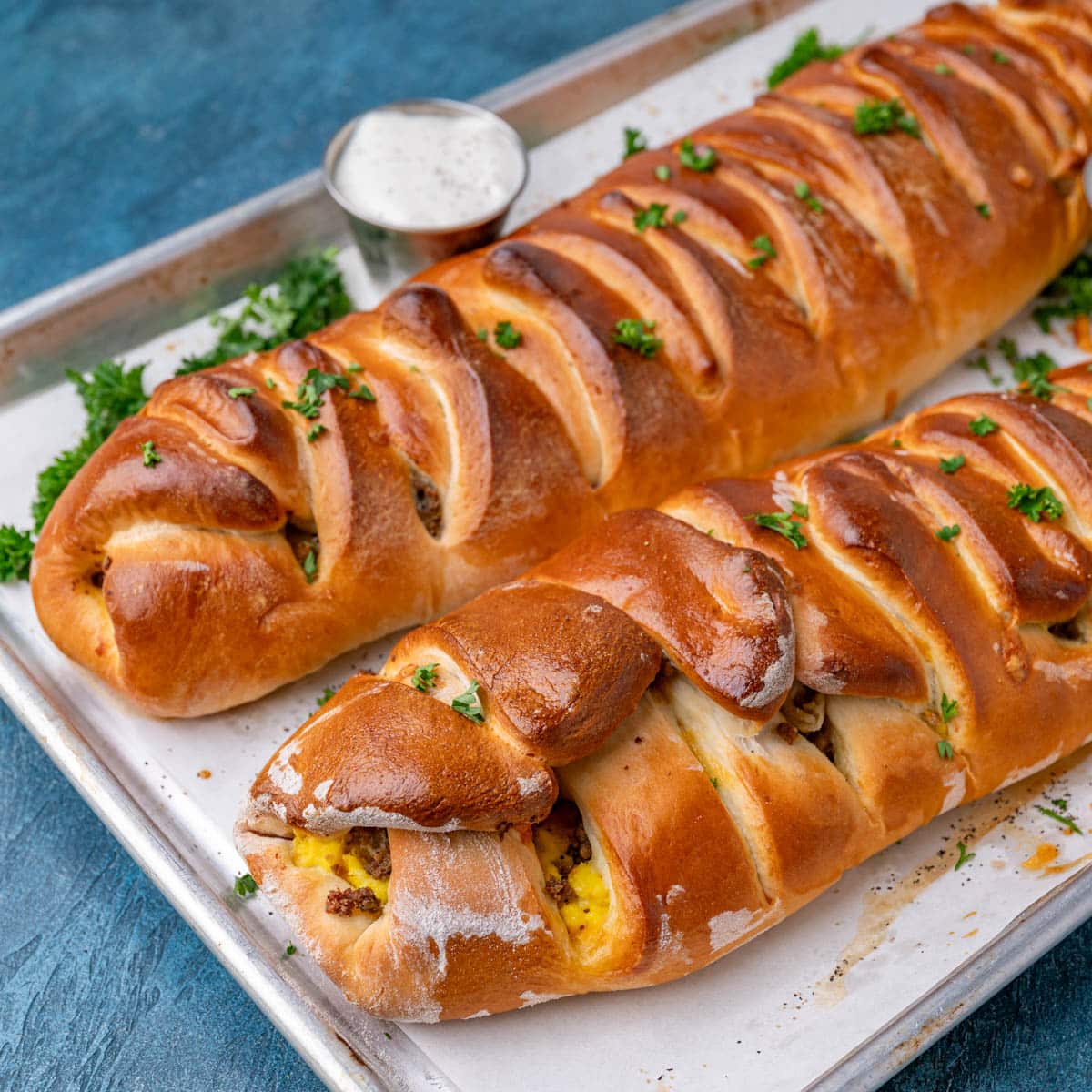 two breakfast stromboli with a braided top on a baking sheet