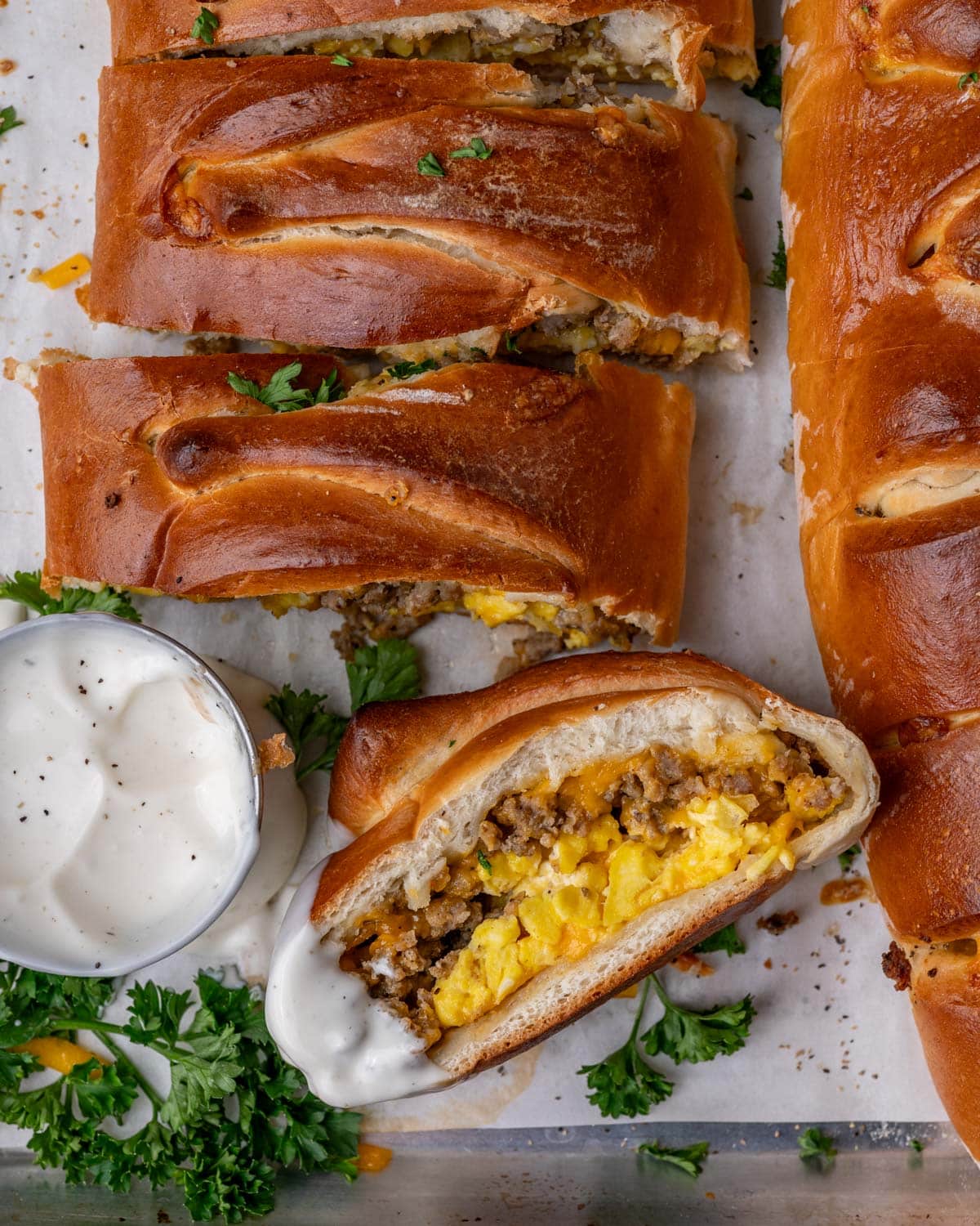 breakfast stromboli sliced on a baking sheet with a cup of ranch dressing