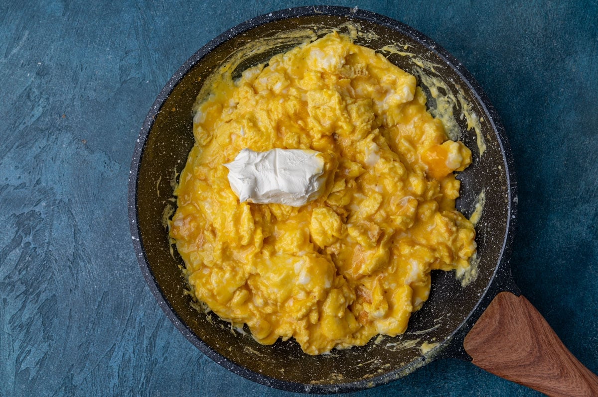 partially scrambled eggs with cream cheese sitting on top