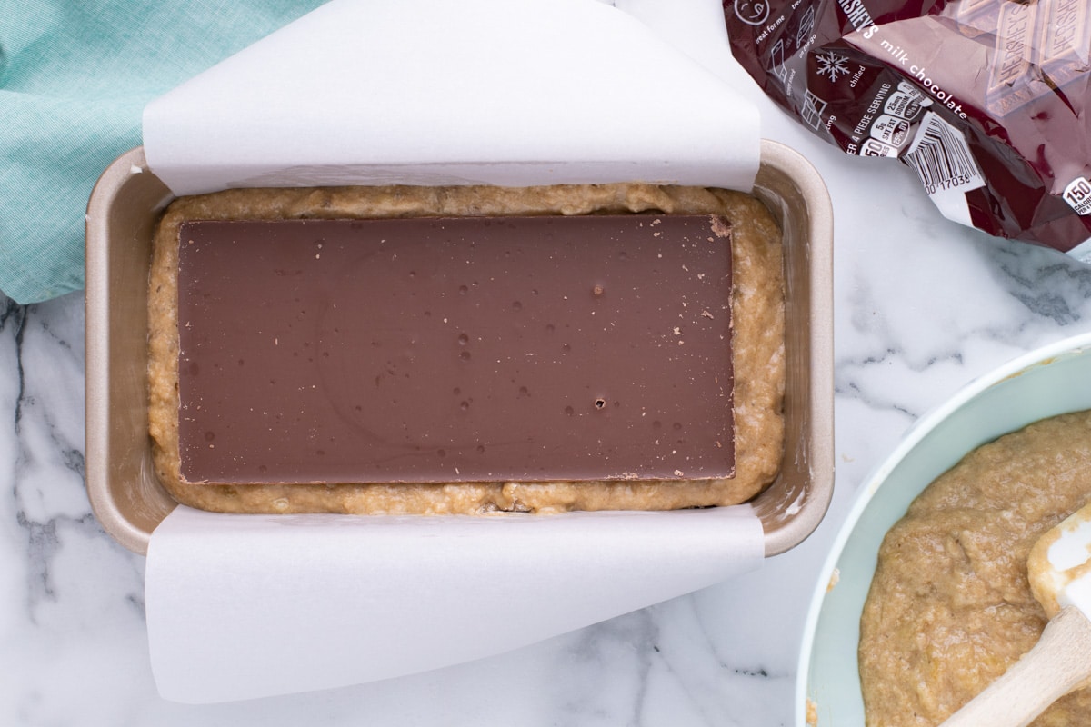 unbaked banana bread batter with a chocolate bar laying on top