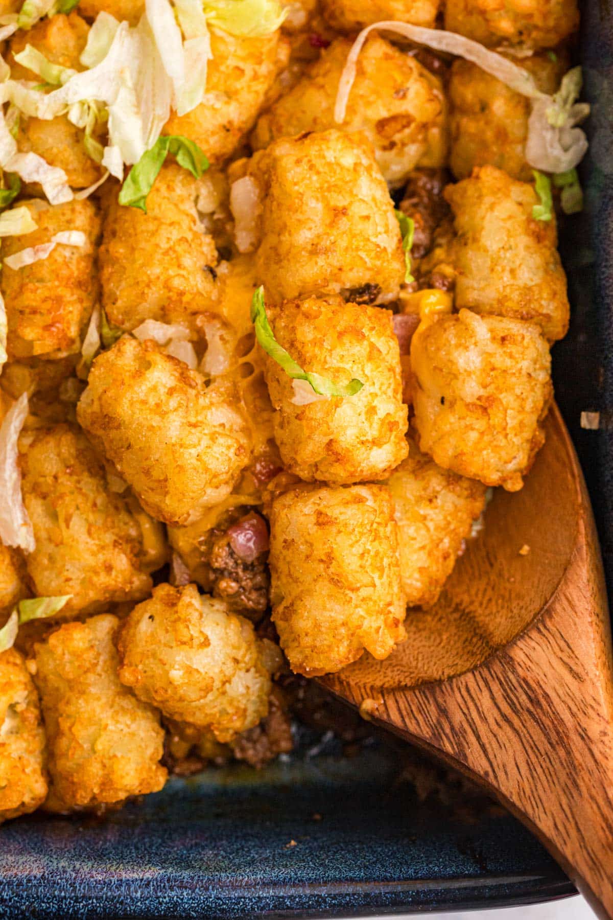 cheeseburger tater tot casserole in a pan with a spatula