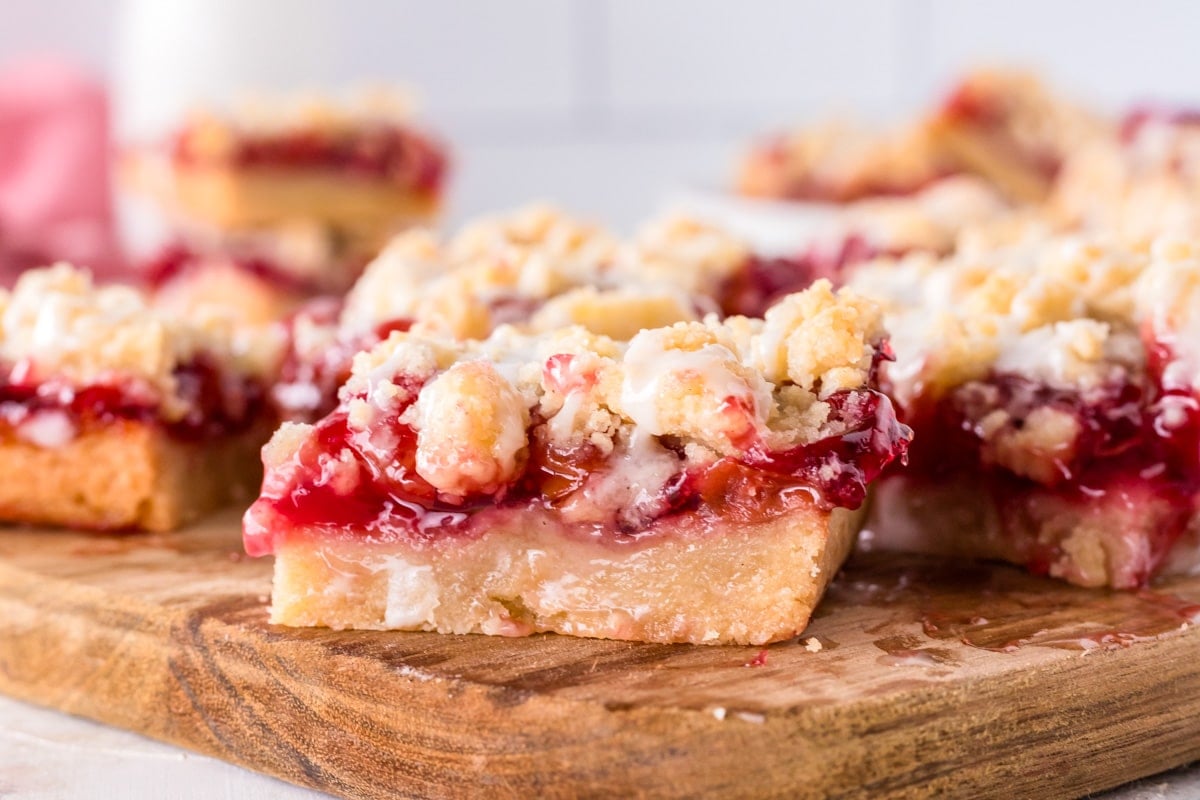 cherry pie bars with streusel and glaze on a wooden cutting board