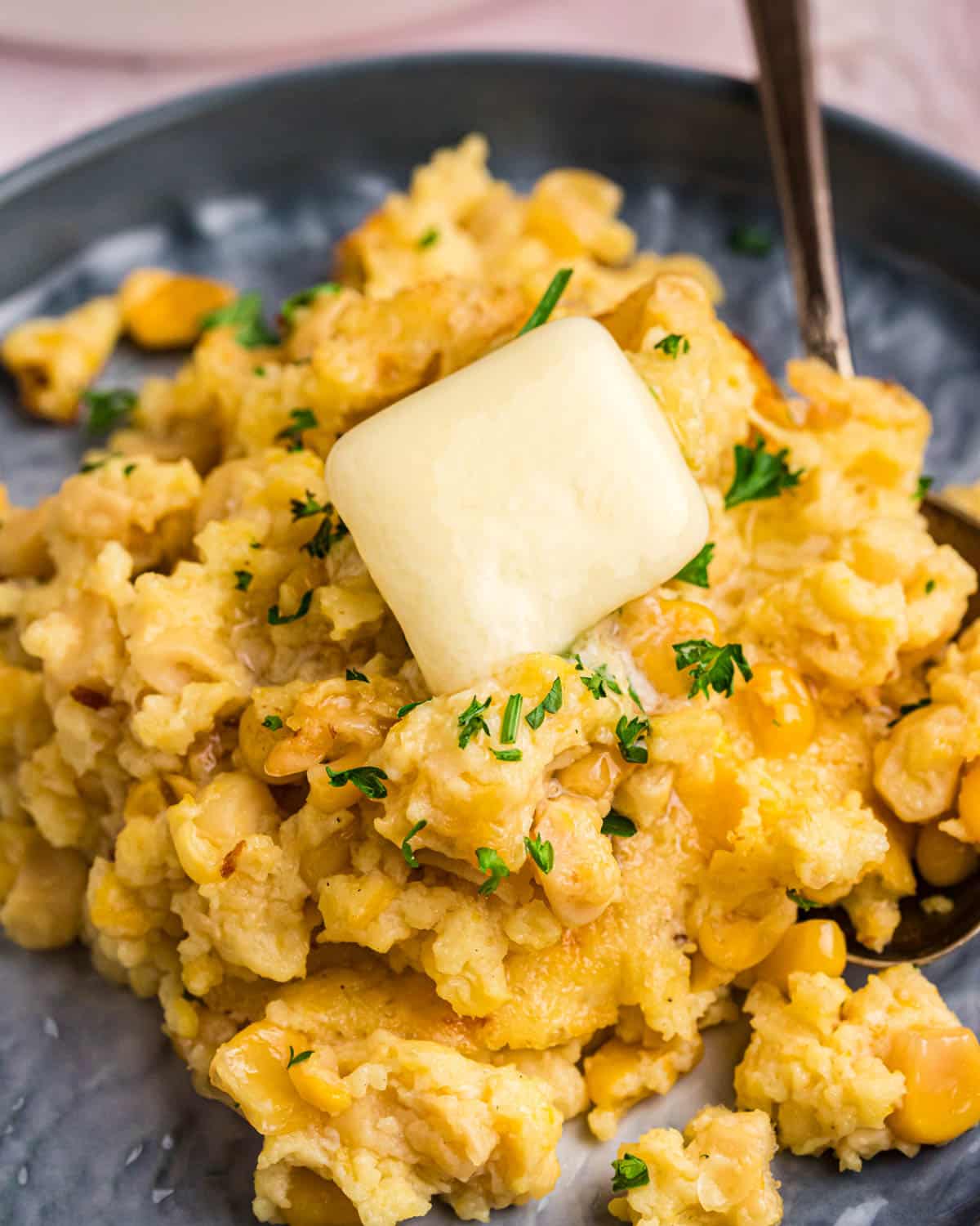 corn casserole pudding on a plate with a pad of butter on top