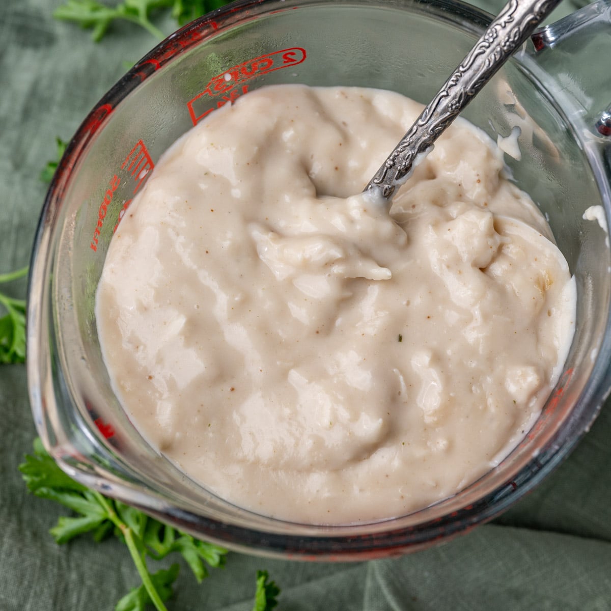 a glass measuring cup and spoon with condensed cream of chicken soup in it