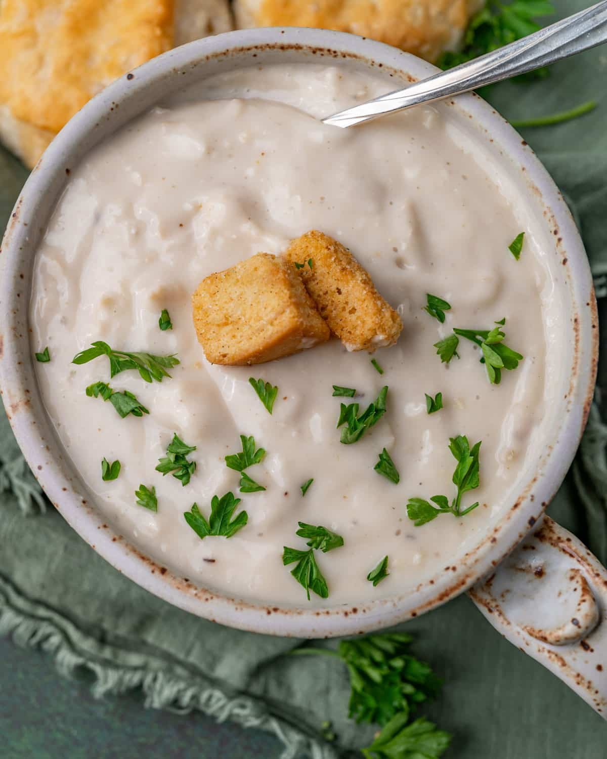 overhead view of a bowl of soup with a spoon and croutons