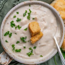 a bowl of cream of chicken soup with croutons and parsley