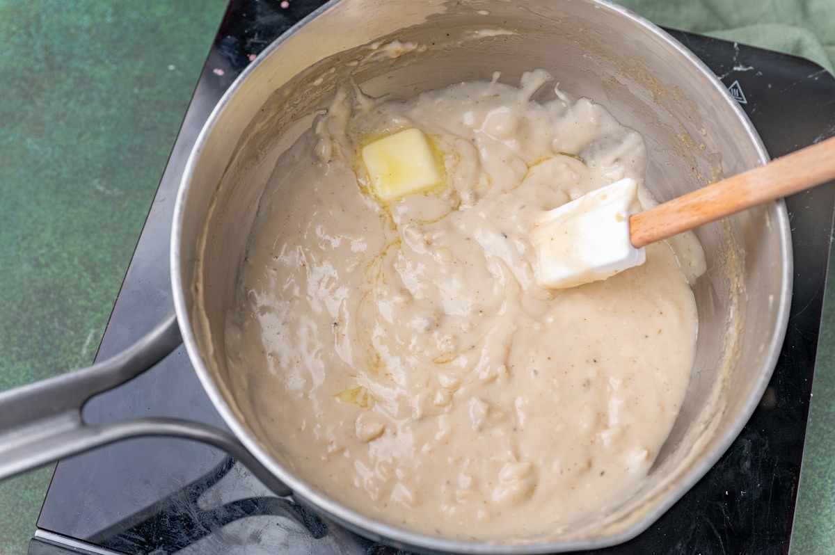 a pan of cream of chicken soup with a pad of butter melting in it