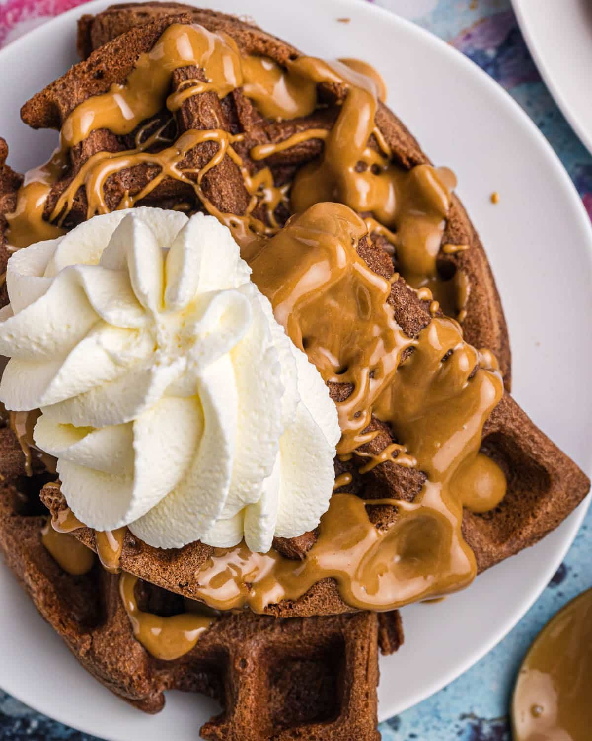 a plate of waffles with melted peanut butter and whipped cream