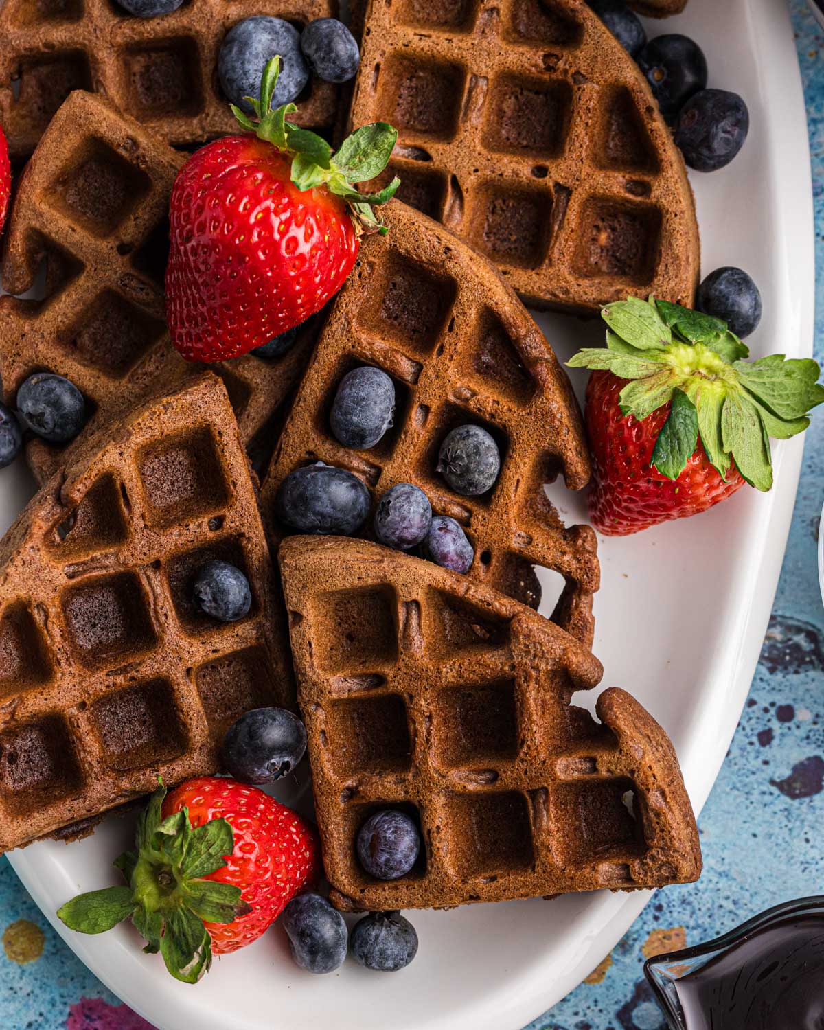 a plate of chocolate flavored waffles with blueberries and strawberries