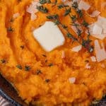 overhead view of mashed butternut squash in a bowl with fresh thyme, butter and parmesan