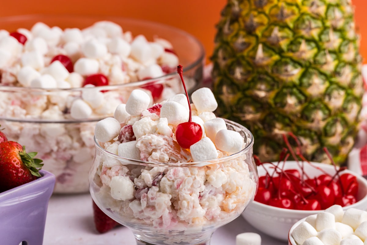 glorified rice fruit salad in a serving bowl with a cherry on top