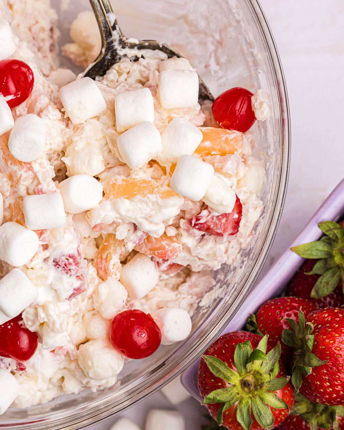 a bowl of glorified rice fruit salad with cherries and marshmallows