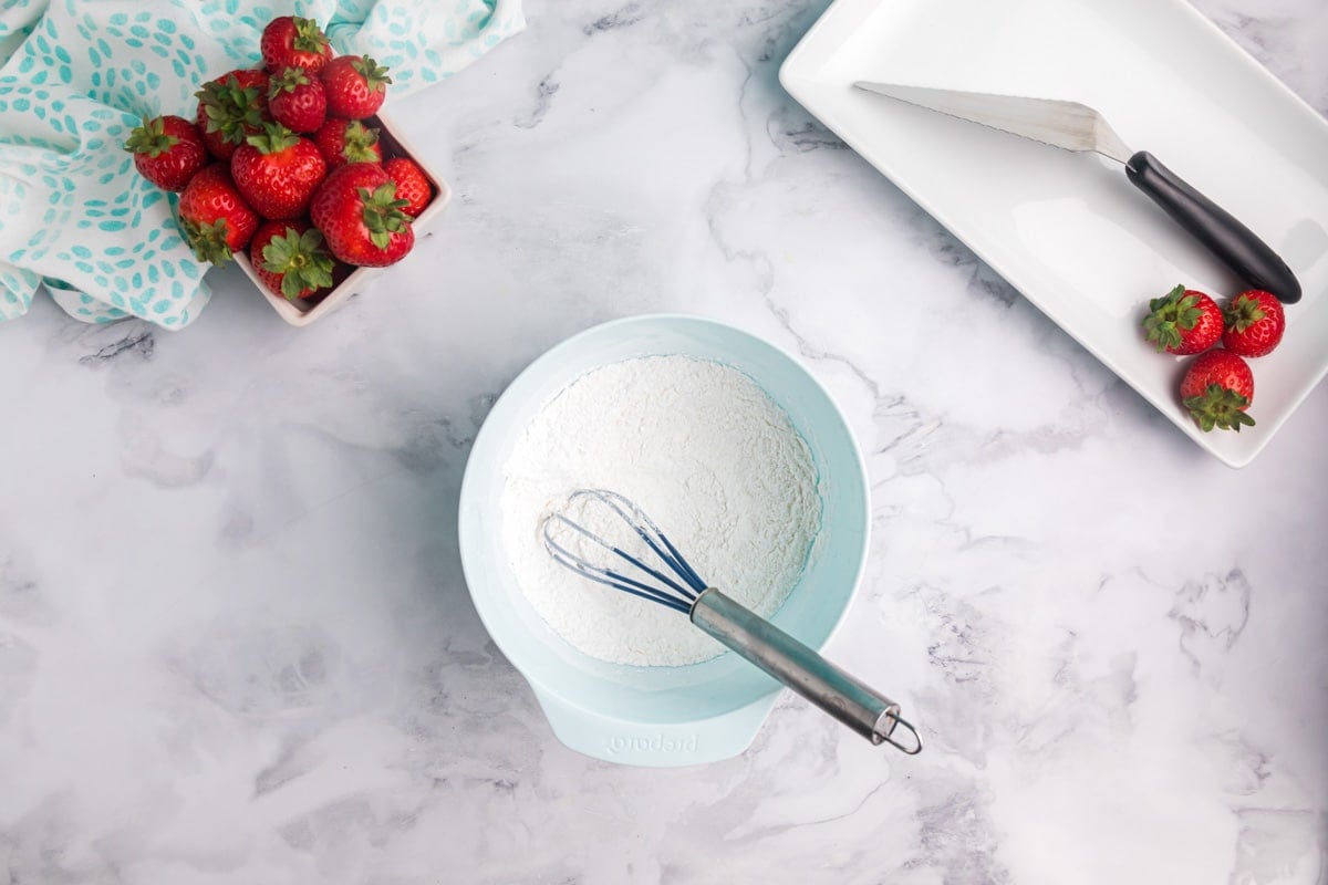 dry ingredients for angel food cake mixed in a bowl with a whisk