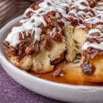 maple pecan sticky buns on a plate with one missing