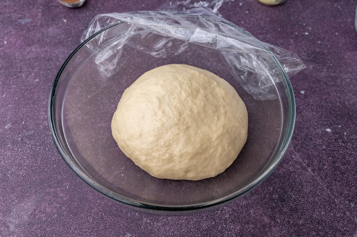 sticky bun dough in a glass bowl to rise